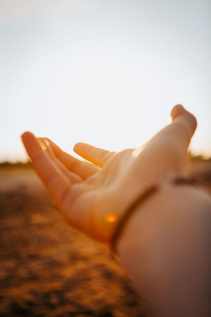 Crafting Captivating Headlines: Your awesome post title goes here A hand reaching up against a sunlit sky at sunset, creating a warm, inviting scene.